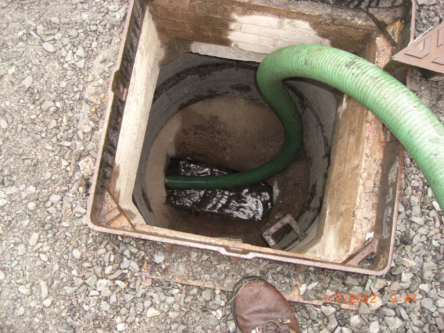 Green suction hose emptying a septic tank