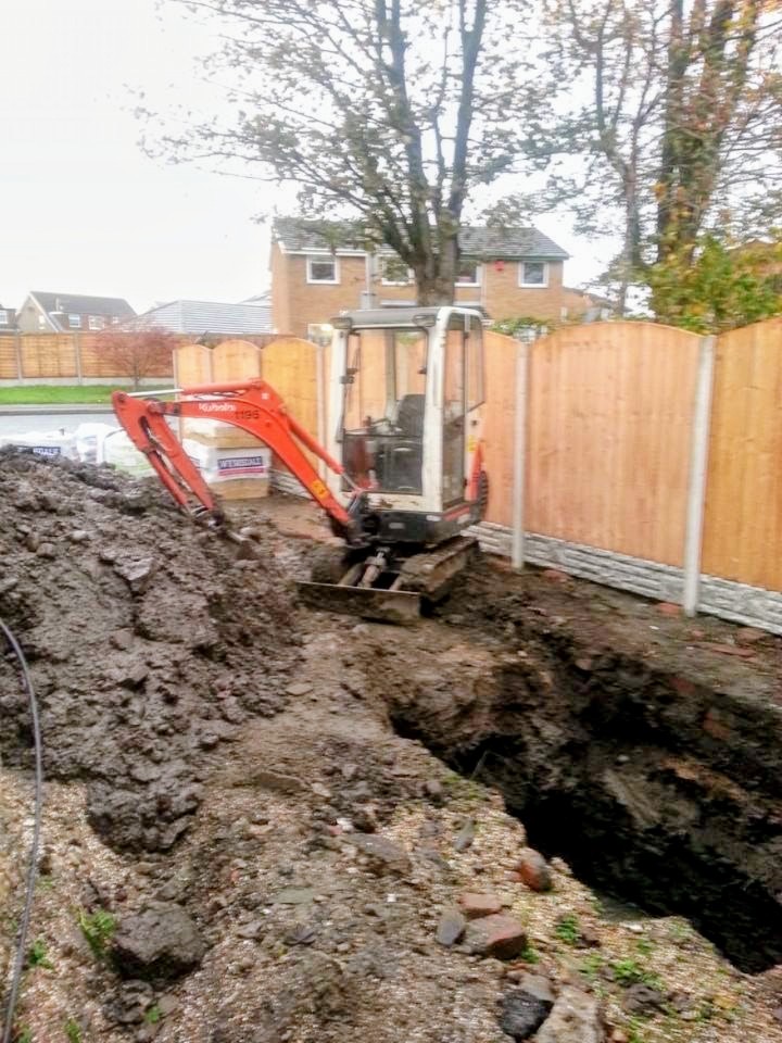 Mini excavator digging a drainage trench in a garden