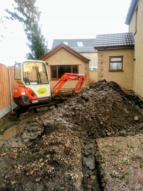 Mini excavator carrying out groundworks beside a house